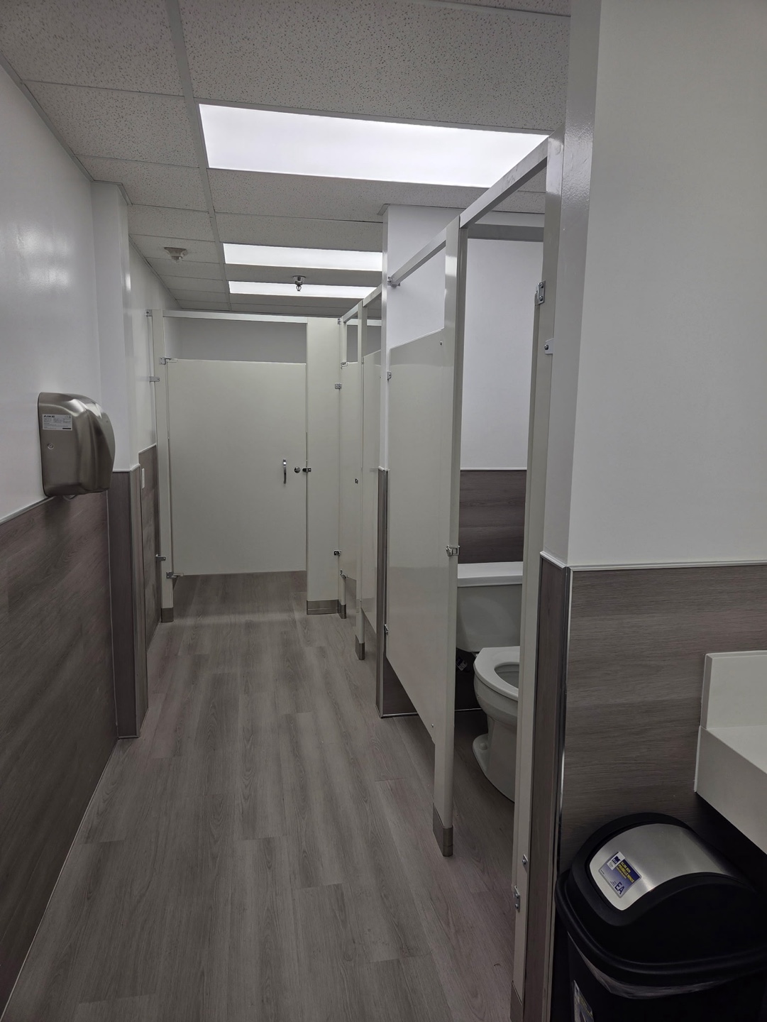 Finished commercial restroom corridor with partitions