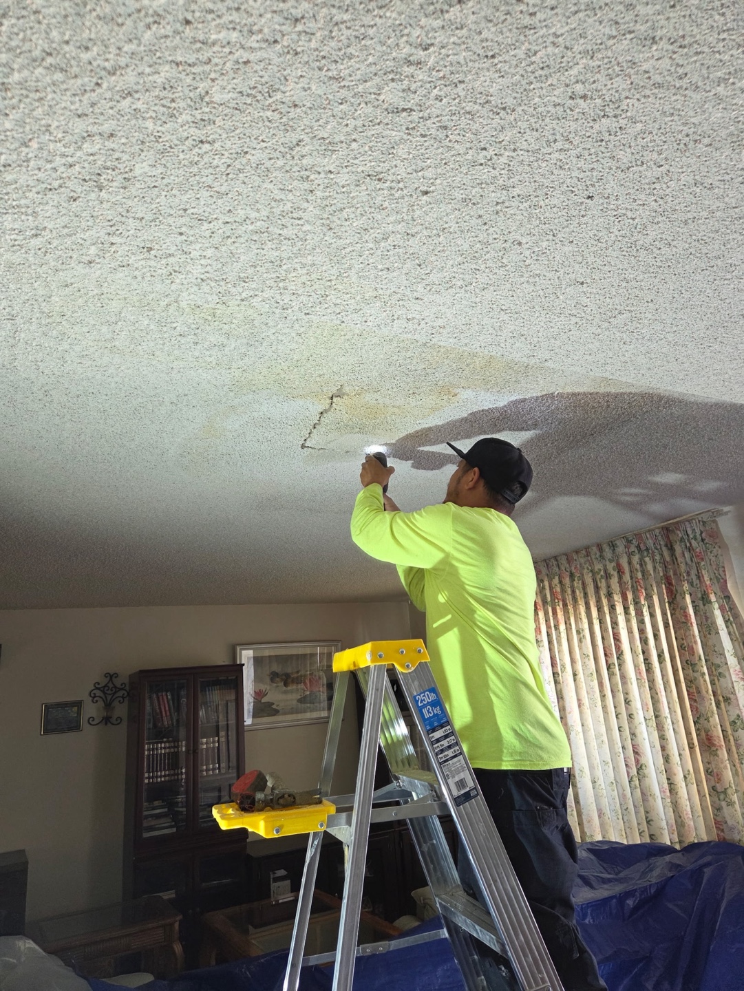 Crew member repairing a ceiling after pipe access